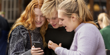 en gruppe unge ser på en mobiltelefon
